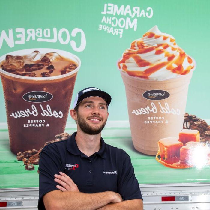 Kwik Trip driver with arms crossed, smiling and standing next to a KT semi advertising KT’s cold and frozen drinks