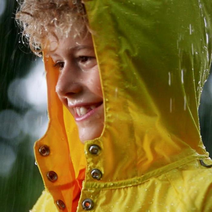 身穿黄色雨衣的男孩带着兜帽，这是健康保险公司的视频.