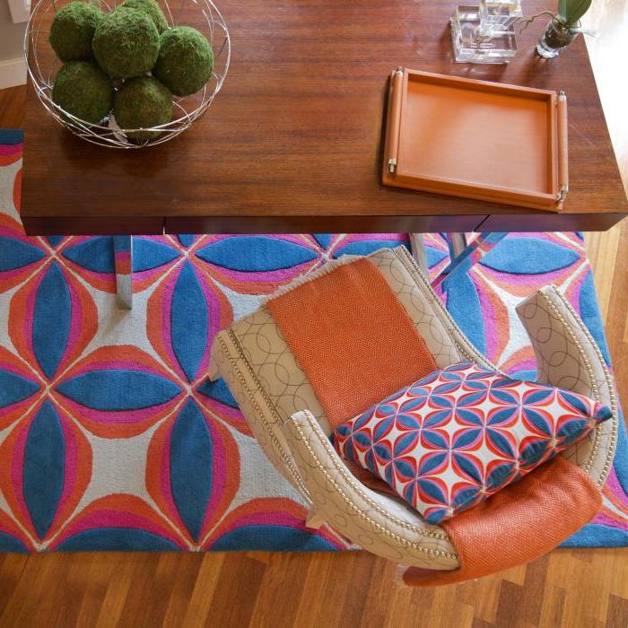 公司房间，有蓝色的地毯和枕头, orange and white, 奶油色的椅子，橙色的靠垫, wooden desk and décor