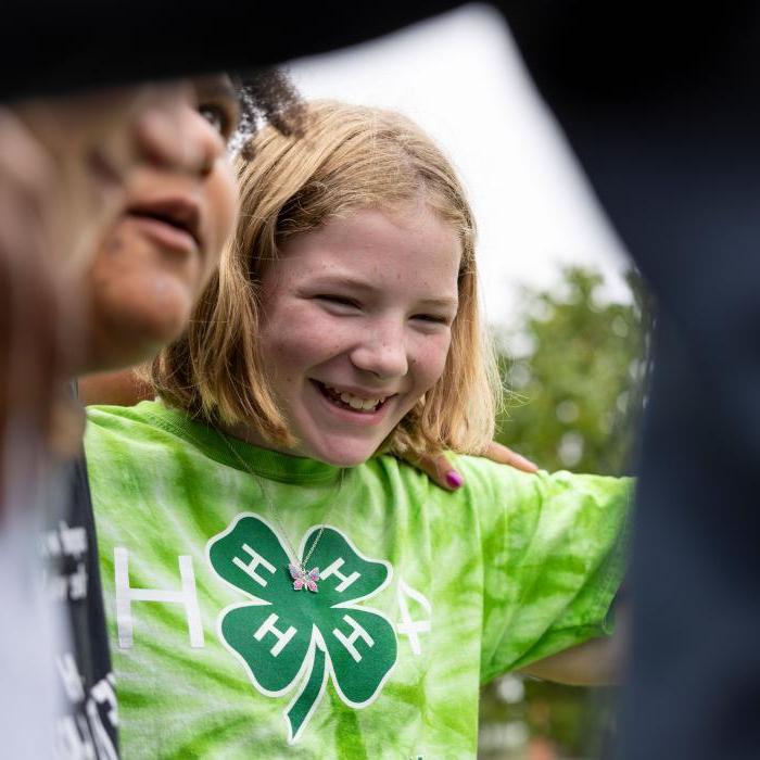 Happy young girl wearing a green four leaf clover 4-H shirt.