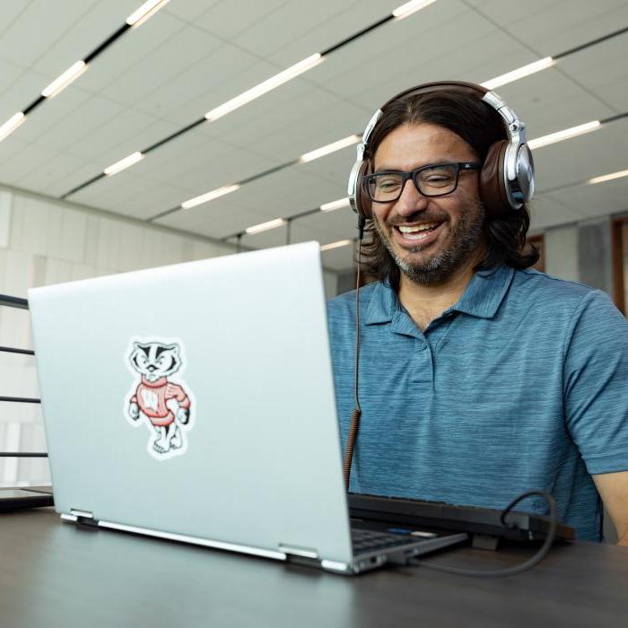 威斯康星大学麦迪逊分校的一名学生远程工作，在会议中对着笔记本电脑微笑