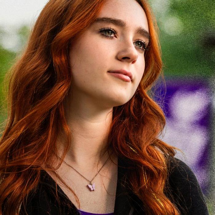 A woman with red hair looks off into the distance.